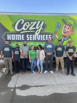 Eight people stand in front of a Cozy Home Services truck with a cartoon handyman graphic and company logo, posing for a group photo on a sunny day—ready to answer your questions about water filtration and how reverse osmosis works.